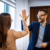 Man en vrouw geven elkaar lachend een high five in een kantoor
